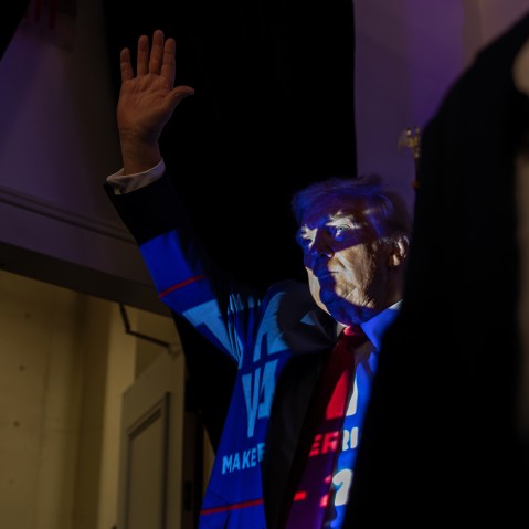 Donald Trump in Charlotte, N.C., with a projection of a Trump 2024 poster casting onto him.
