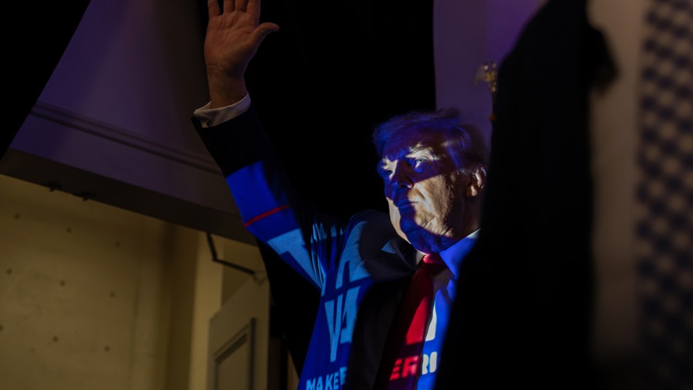 Donald Trump in Charlotte, N.C., with a projection of a Trump 2024 poster casting onto him.