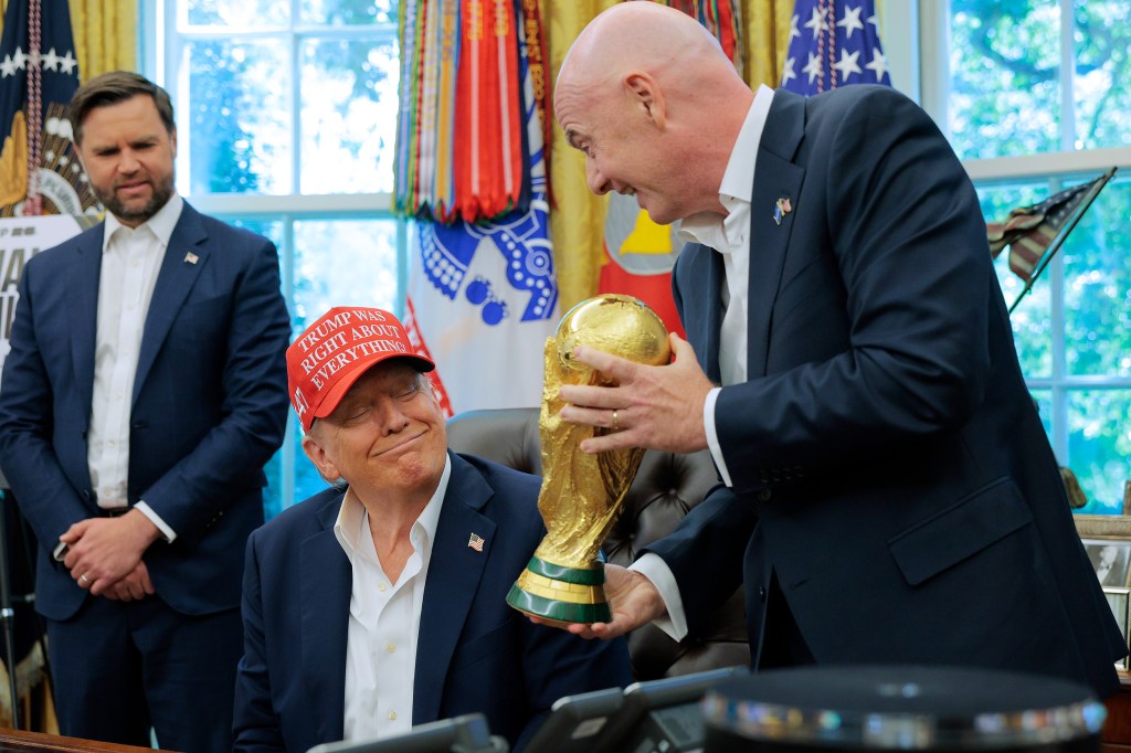 FIFA President Gianni Infantino, right, shows President Donald Trump the World Cup Trophy in the Oval Office as Vice President JD Vance looks.