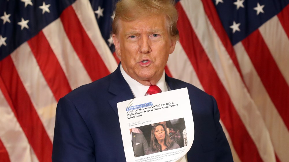 Then former U.S. President Donald Trump holds up a news story about New York Attorney General Letitia James as he speaks to the media at one of his properties at 40 Wall Street following closing arguments at his civil fraud trial on Jan. 11, 2024, in New York City.