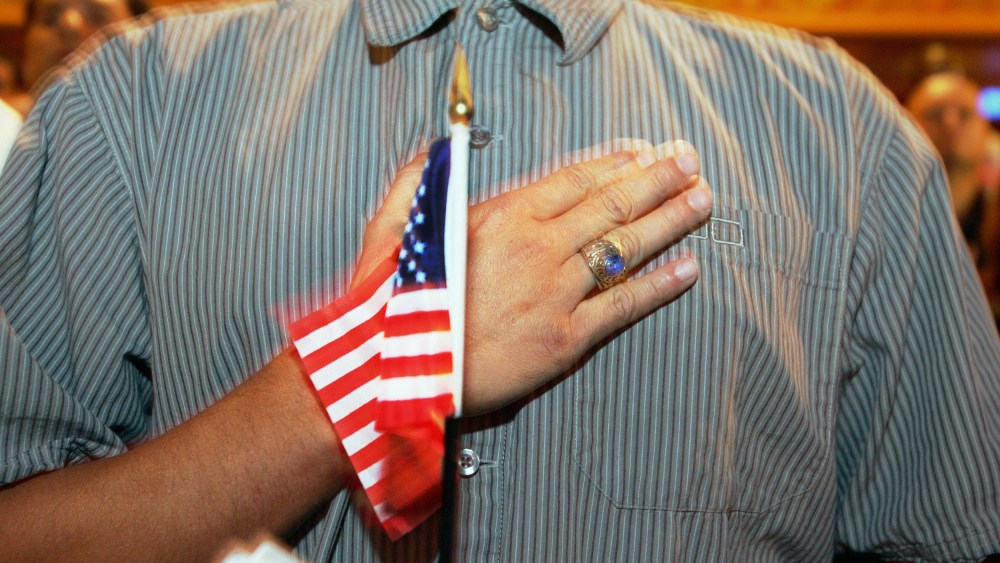 A person holds their hand up to their chest as they swear allegiance to the U.S. flag during a naturalization ceremony in Miami, F.L., on April 28, 2006.