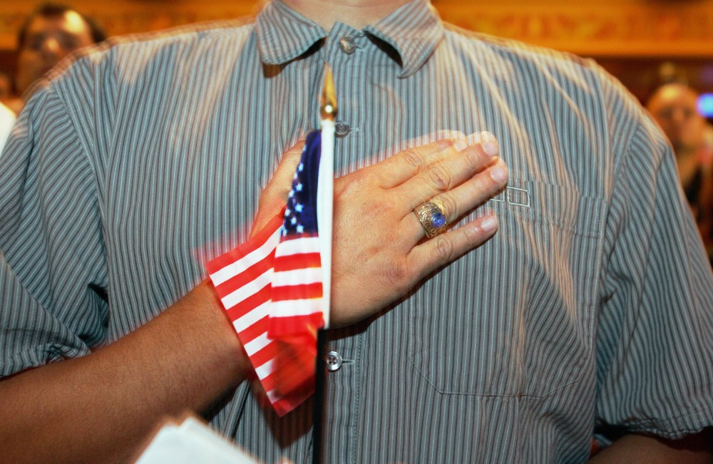 A person holds their hand up to their chest as they swear allegiance to the U.S. flag during a naturalization ceremony in Miami, F.L., on April 28, 2006.