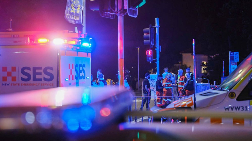 Emergency responders at Sydney’s Bondi Beach confer amid the flashing lights of EMS vehicles.