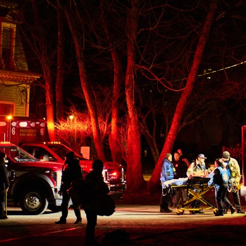 First responders wheel an empty gurney into an ambulance on Brown University campus.