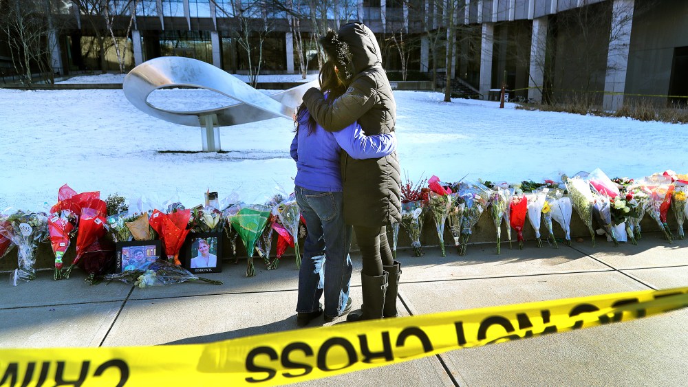 People hug in front of a memorial at Brown University.