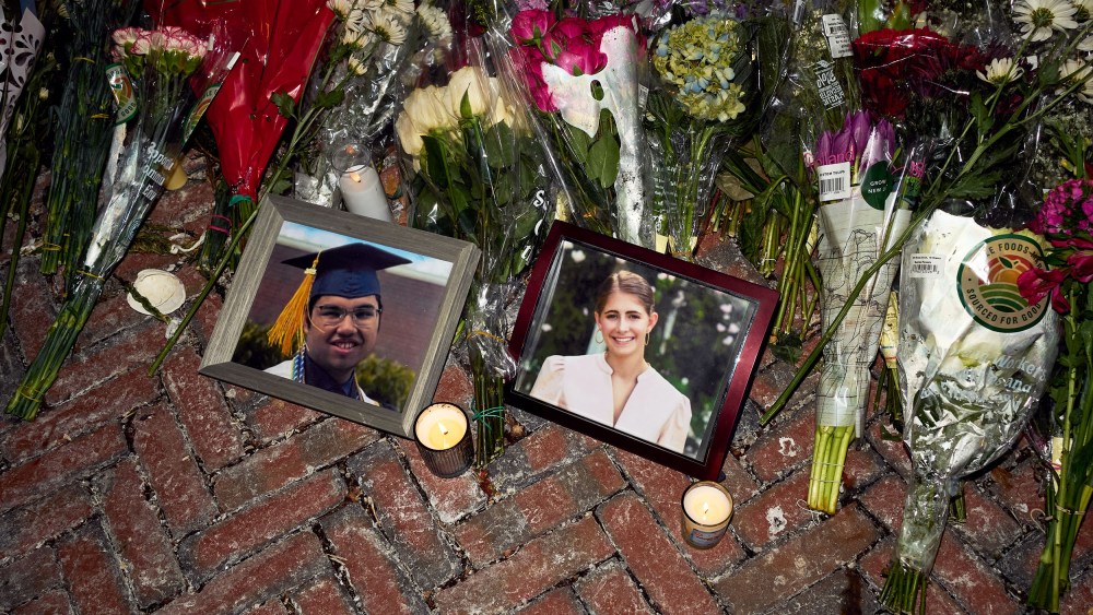 Lit candles and flowers rest by framed photos of mass shooting victims MukhammadAziz Amurzokov and Ella Cook at a memorial near Brown University.