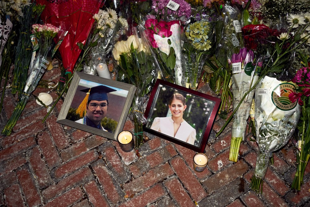 Lit candles and flowers rest by framed photos of mass shooting victims MukhammadAziz Amurzokov and Ella Cook at a memorial near Brown University.