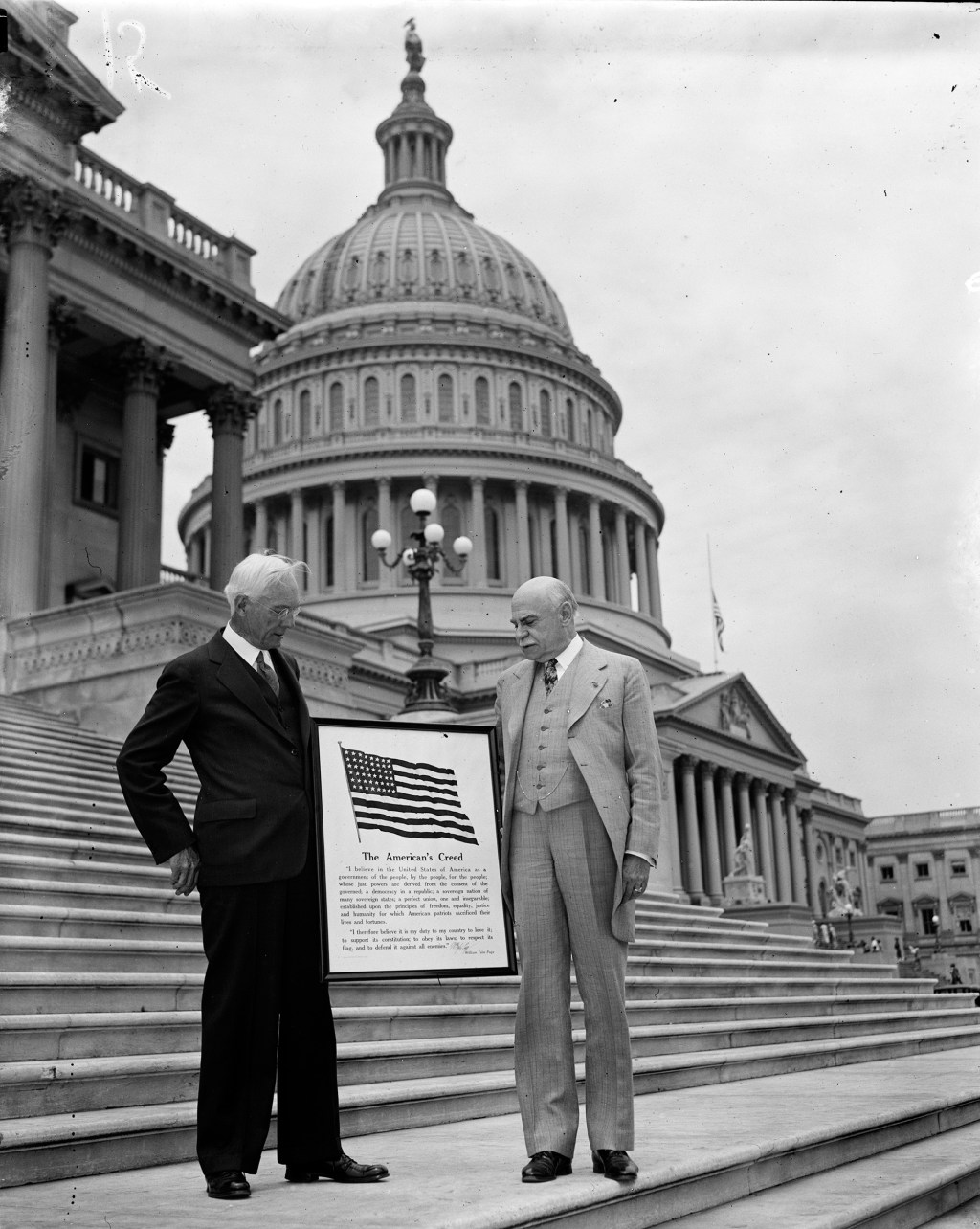 American civil servant and Clerk of the House of Representatives William Tyler Page, right, and an unidentified man hold a poster of "The American’s Creed" in front of the Capitol in 1936.
