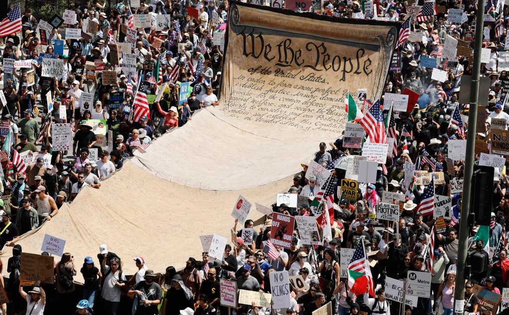 Protesters surround a banner representing the Preamble to the U.S. Constitution in downtown Los Angeles during an anti-Trump "No Kings Day" demonstration.