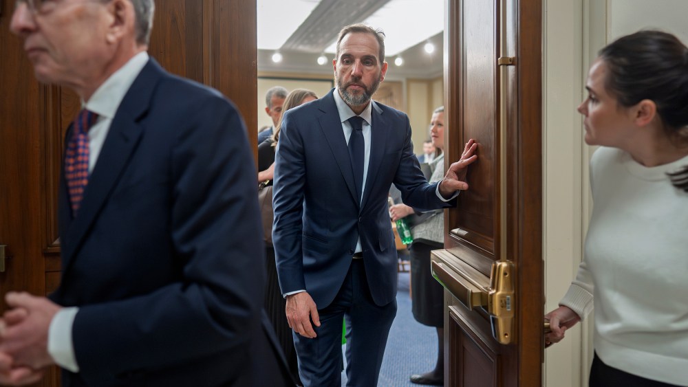 Former Department of Justice Special Counsel Jack Smith, center, walks out of a room.