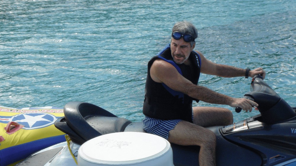Jeffrey Epstein sitting on a jet ski by a dock.
