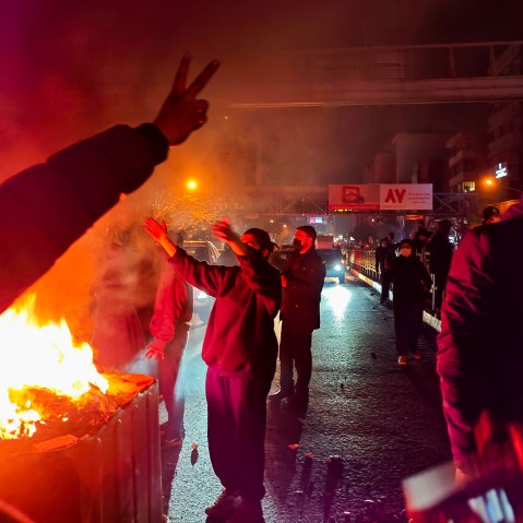 People gather around a fire lit on the streets of Tehran, Iran.