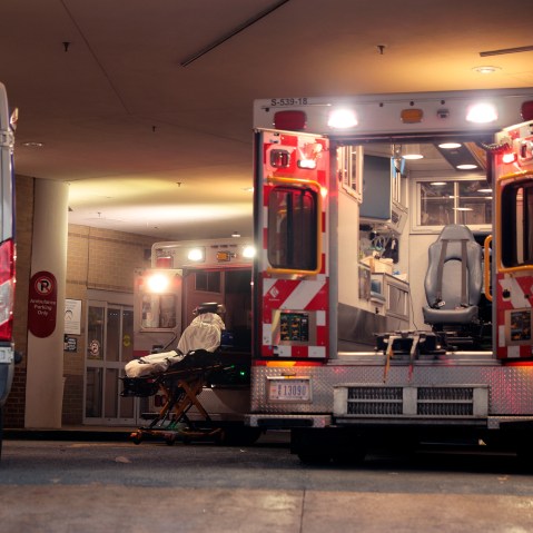 Two ambulances and a gurney in the ambulance bay of a hospital.
