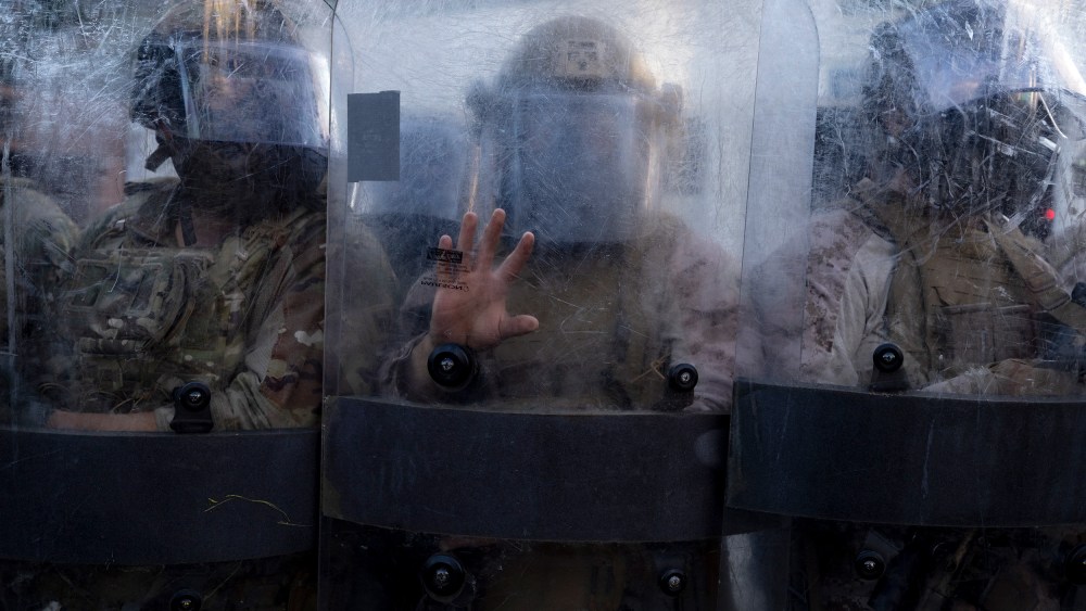 Members of the National Guard and Marines stand behind opaque shields.