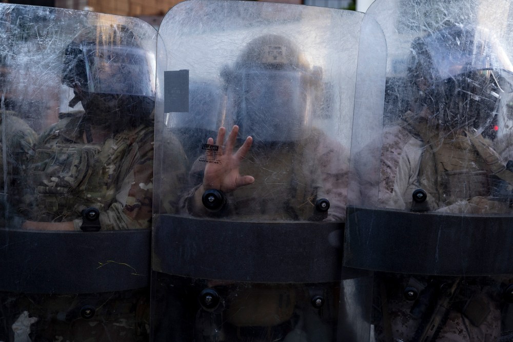 Members of the National Guard and Marines stand behind opaque shields.