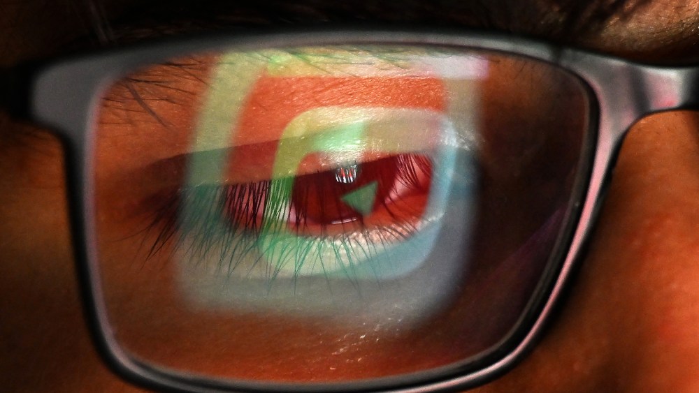 The YouTube logo is reflected in one lens of a person's glasses.