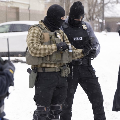 ICE agents check's a man's immigration status on a snowy street in Minnesota.