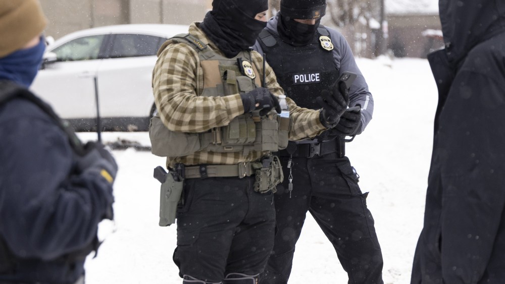 ICE agents check's a man's immigration status on a snowy street in Minnesota.