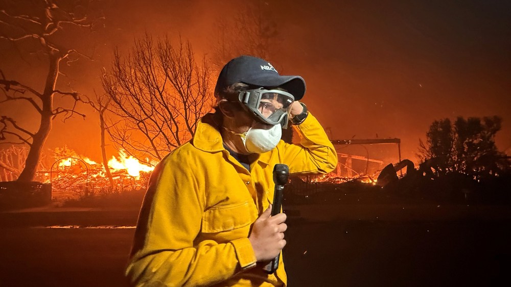 MS NOW's Jacob Soboroff stands with a microphone, wearing a face mask as Palisades fire continues in the background.