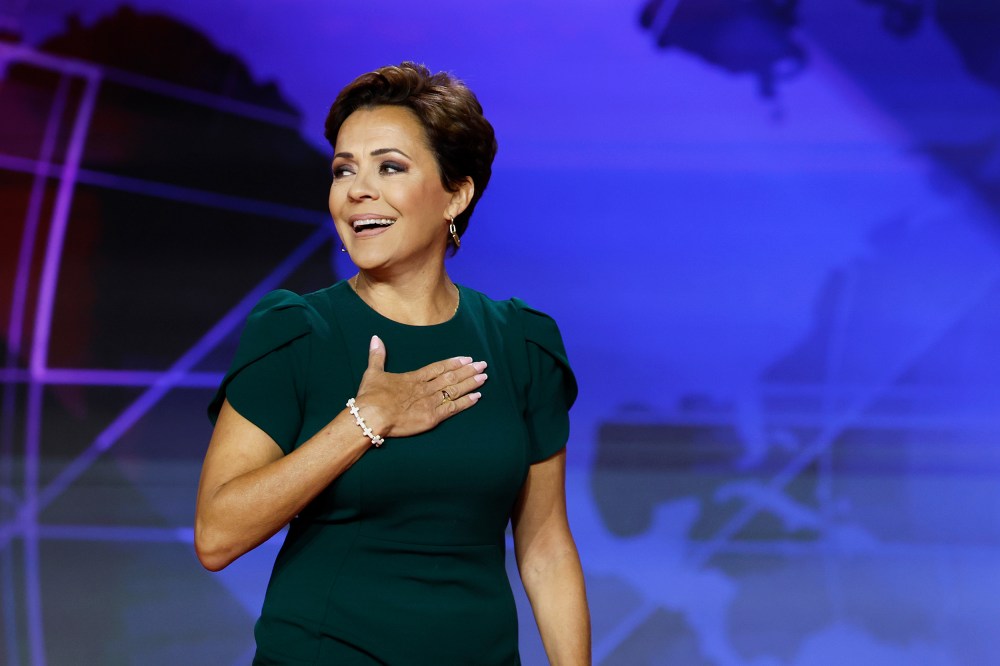 Kari Lake holds her hand on her chest.