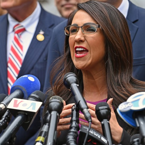 Lauren Boebert speaks into news channels' microphones at a press conference.