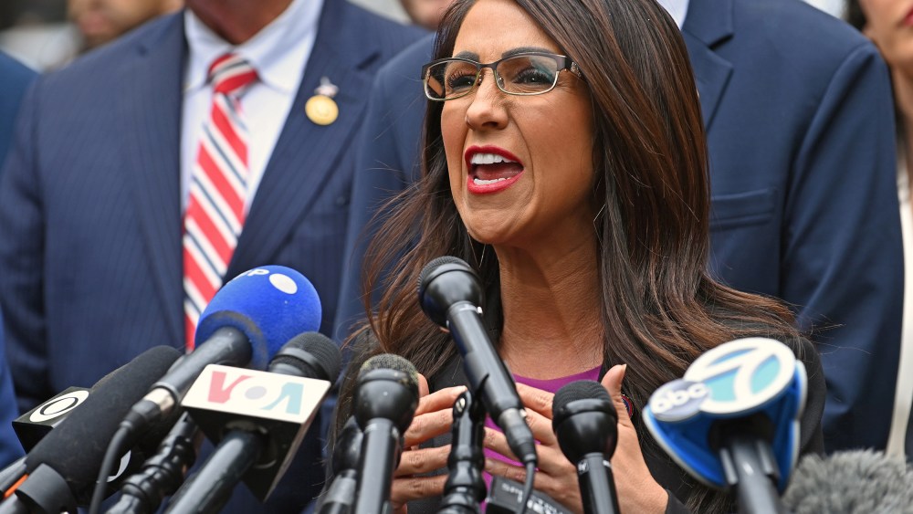 Lauren Boebert speaks into news channels' microphones at a press conference.