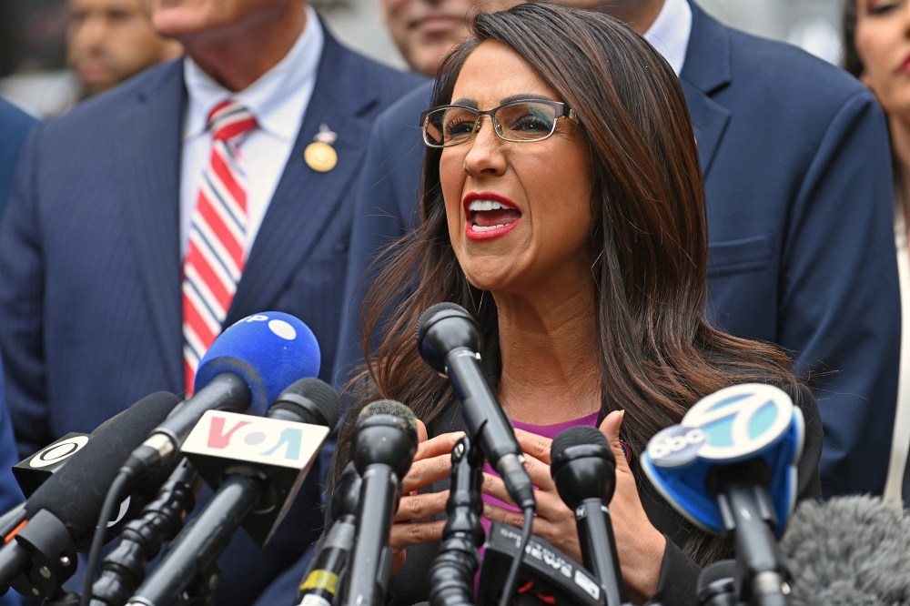 Lauren Boebert speaks into news channels' microphones at a press conference.