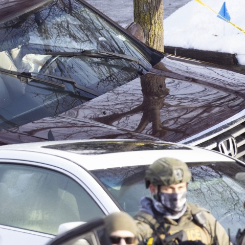 ICE agents next to a car crashed into a post.