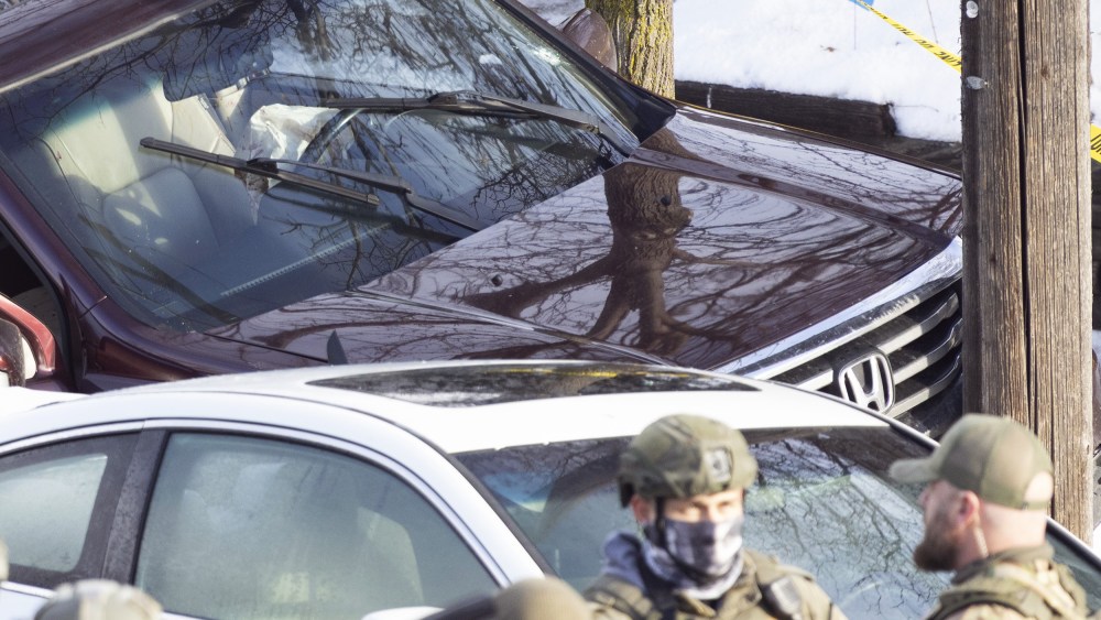 ICE agents next to a car crashed into a post.