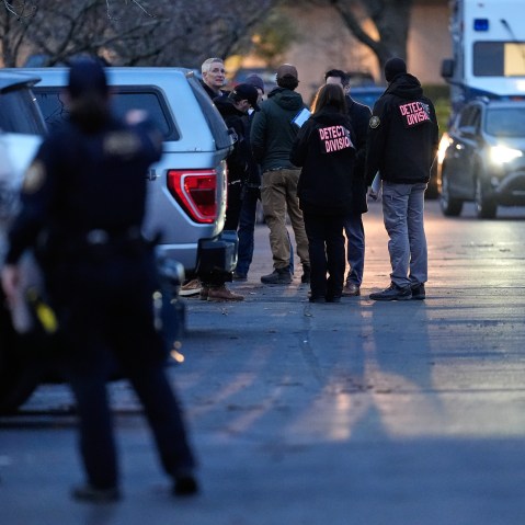 Members of the law enforcement stand in the street at dusk.