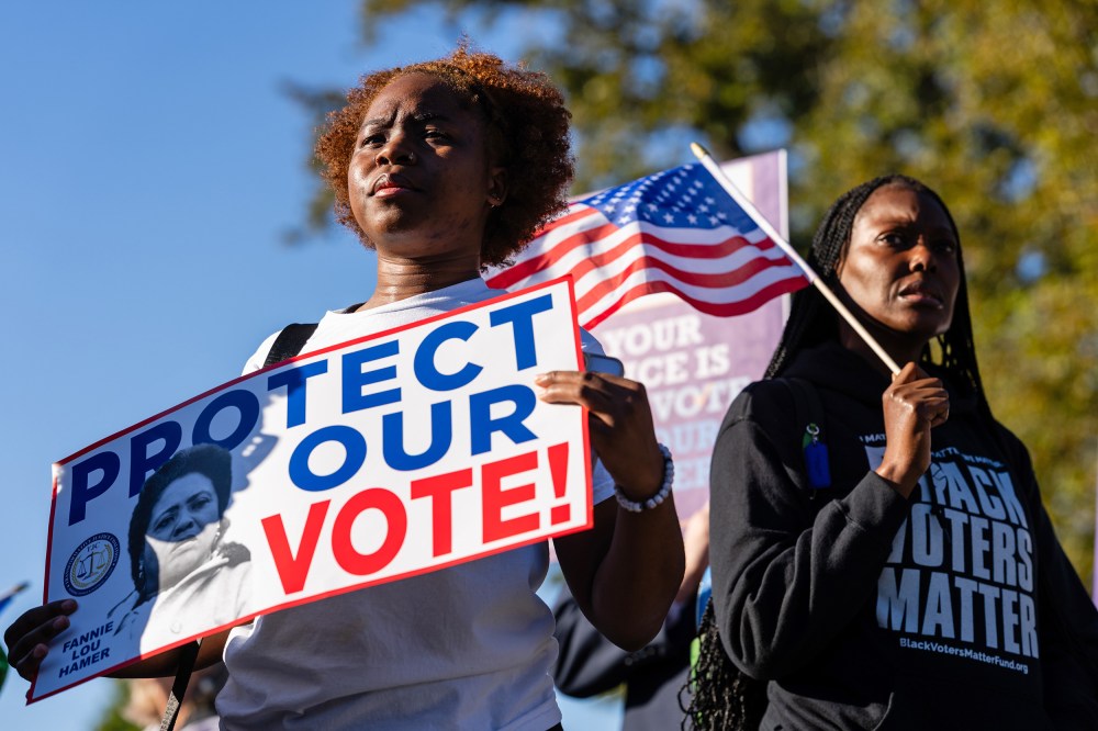 Two people hold signs and American flags in support of Black voters.