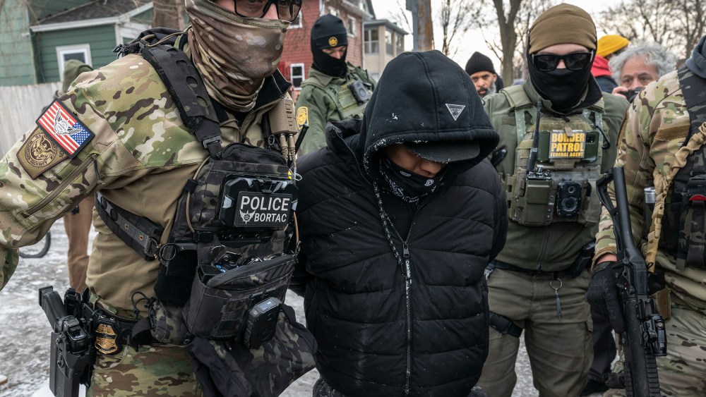 Federal agents wearing body cams detain a person.