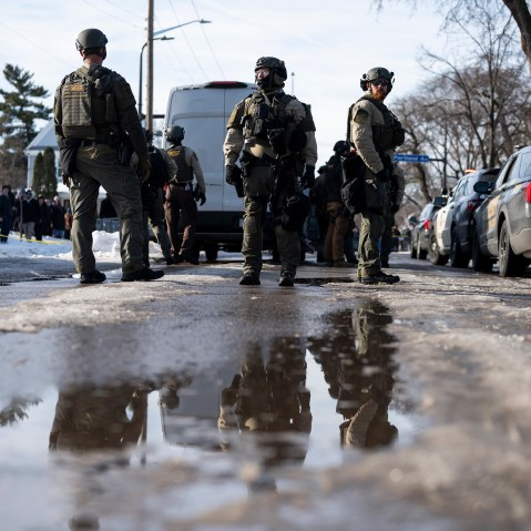 Law enforcement and officers stand in the street.