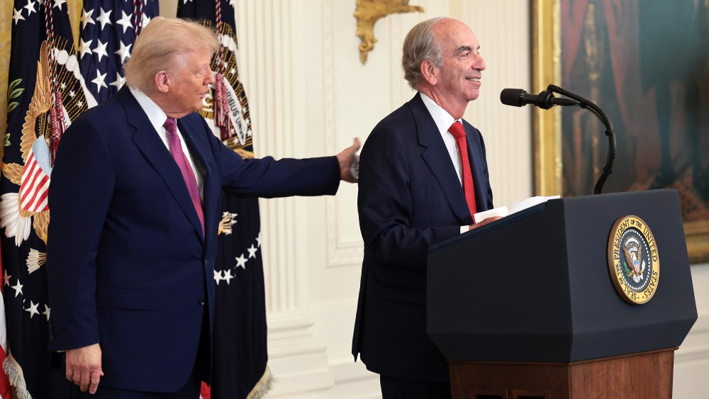 President Donald Trump pats the back of John Hess as he delivers remarks on June 12, 2025 in the East Room of the White House.