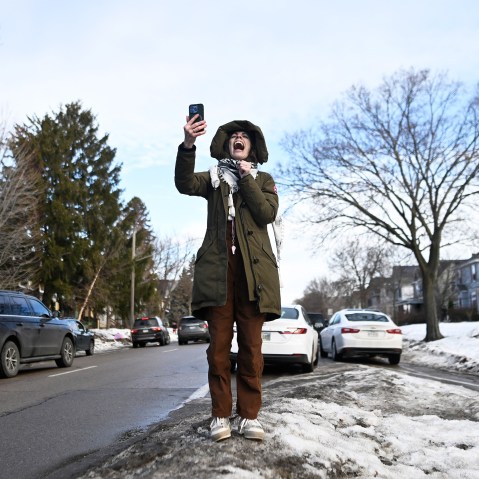 A person yells while holding up a cell phone.
