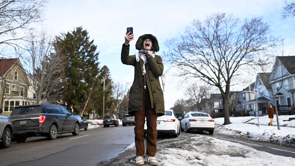 A person yells while holding up a cell phone.