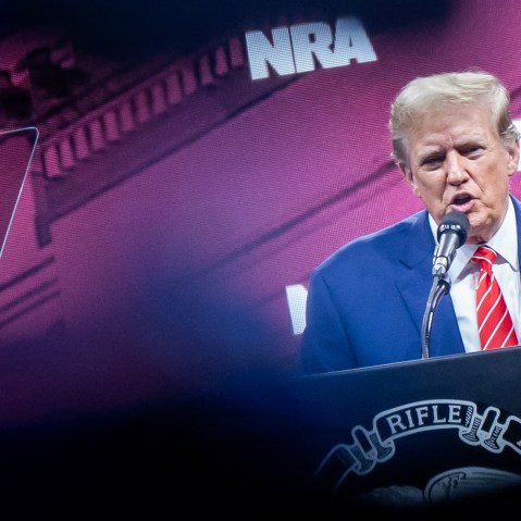 President Trump speaks at an NRA convention on stage.