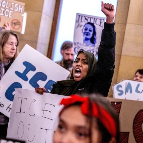 A female protestor shouts with her left fist raised during a protest.