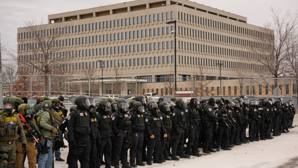 A crowd of federal immigration officers in helmets stand outside the Whipple Federal Building.