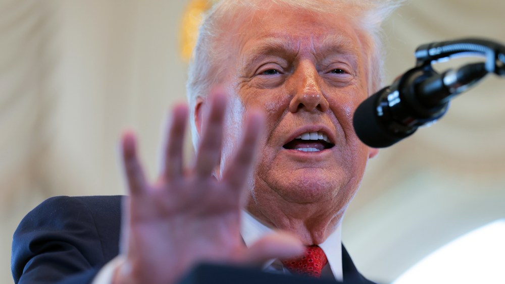 Donald Trump gestures with his hand in front of a microphone.