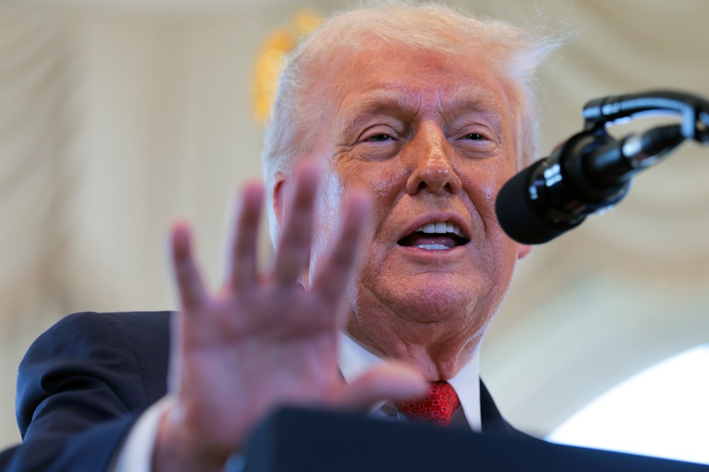 Donald Trump gestures with his hand in front of a microphone.