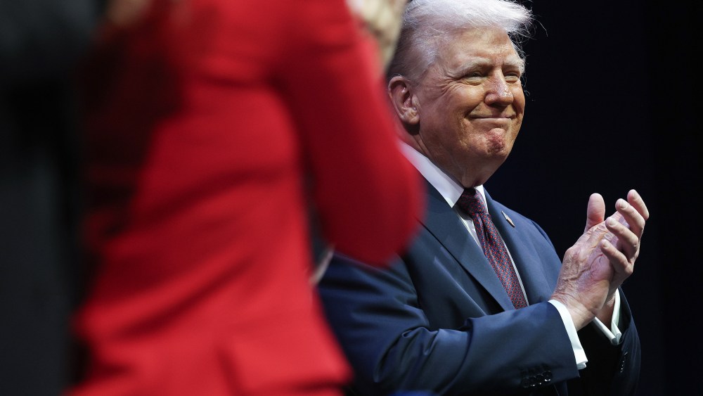 Donald Trump claps with a smile on his face.