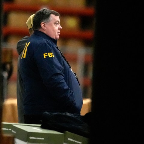 An FBI agent is seen standing near green boxes.