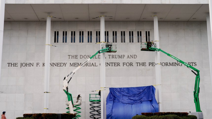 Workers affix signage adding President Donald Trump's name on the facade of the Kennedy Center in Washington, D.C.