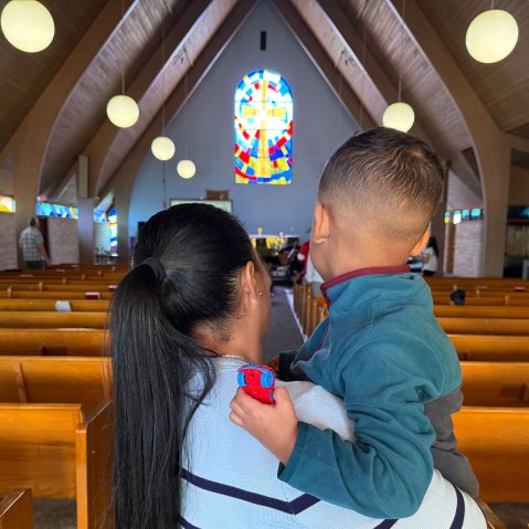 A woman holds a young child in a church
