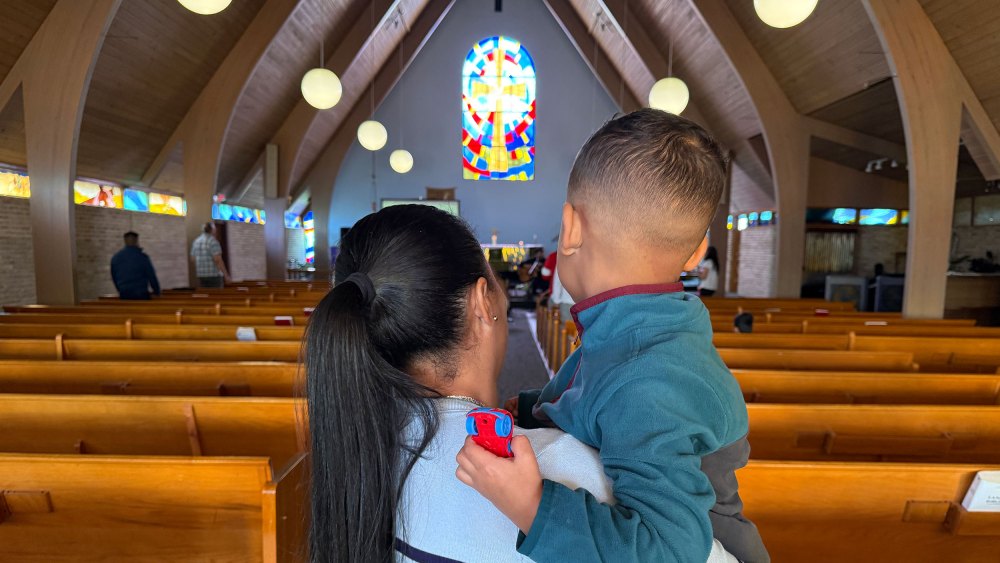 A woman holds a young child in a church