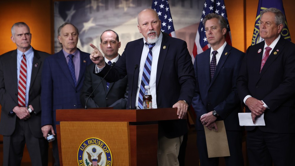 Chip Roy speaks in the foreground while other Freedom Caucus members stand in the background.