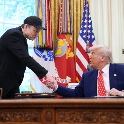Elon Musk, left, and President Donald Trump shake hands in the Oval Office
