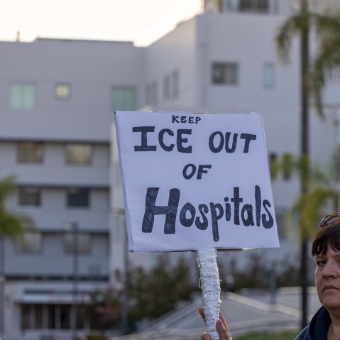 A person holds a sign that reads "Keep ICE out of hospitals."