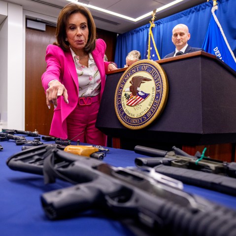Jeanine Pirro, left, points to a table of guns in front of her.